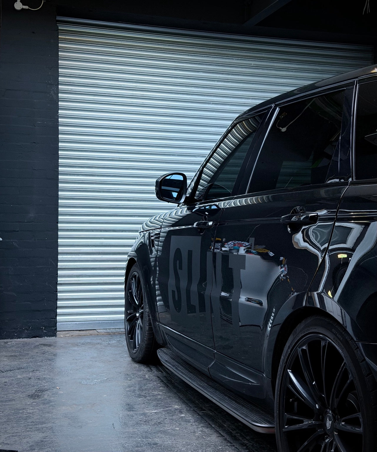 SLNT branding on a black vehicle outside a shuttered garage